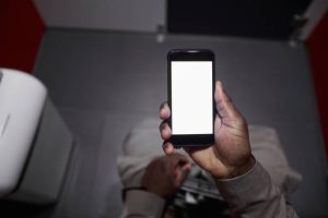 A man using a smartphone while sitting on toilet